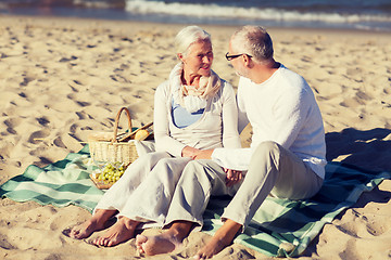 Image showing happy senior couple having picnic on summer beach