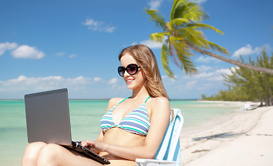 Image showing woman with laptop sunbathing in lounge on beach