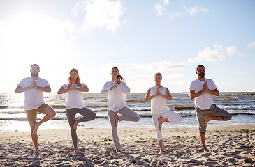 Image showing group of people making yoga in tree pose on beach