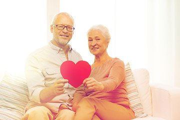 Image showing happy senior couple with red heart shape at home