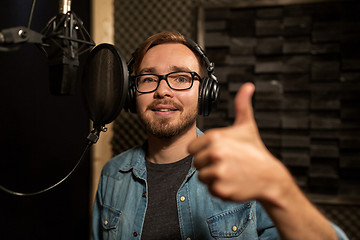 Image showing man with headphones singing at recording studio