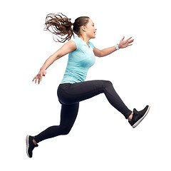 Image showing happy smiling sporty young woman jumping in air