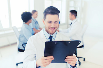 Image showing happy doctor with tablet pc over team at clinic