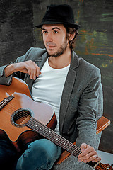 Image showing Cool guy sitting with guitar on gray background