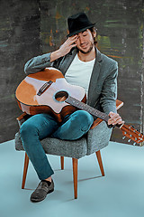 Image showing Cool guy sitting with guitar on gray background