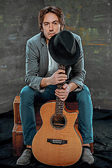 Image showing Cool guy sitting with guitar on gray background