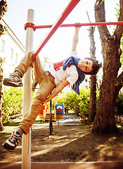 Image showing little cute blond boy hanging on playground outside, alone train