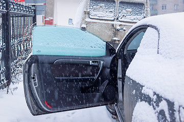 Image showing Opened car door and snowfall in city