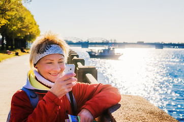 Image showing A woman photographs the phone. Embankment in Riga