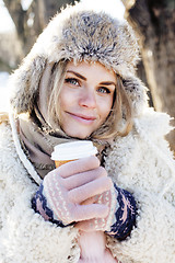 Image showing young pretty teenage hipster girl outdoor in winter snow park having fun drinking coffee, warming up happy smiling, lifestyle people concept