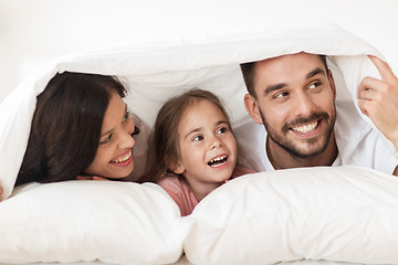 Image showing happy family lying in bed under blanket at home