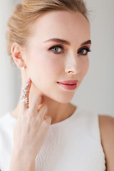 Image showing smiling woman in white dress with diamond jewelry