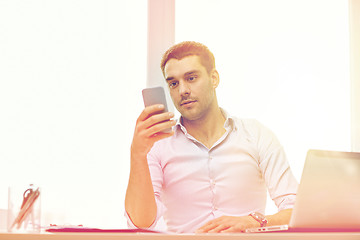 Image showing businessman with smartphone and laptop at office