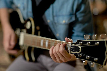 Image showing close up of man playing guitar at studio rehearsal