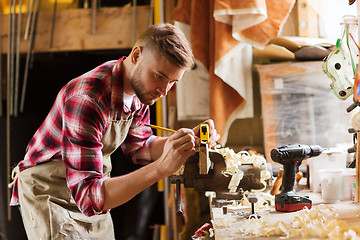 Image showing carpenter with ruler measuring plank at workshop