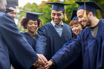 Image showing happy students in mortar boards with hands on top