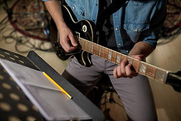 Image showing man with music book on stand playing guitar