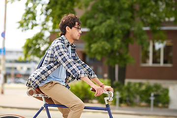 Image showing young hipster man with bag riding fixed gear bike