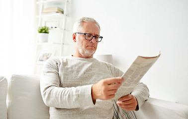 Image showing senior man in glasses reading newspaper at home