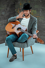 Image showing Cool guy sitting with guitar on gray background