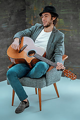 Image showing Cool guy with hat playing guitar on gray background