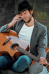 Image showing Cool guy sitting with guitar on gray background