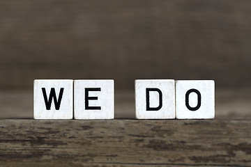 Image showing We do, written in cubes on wooden background