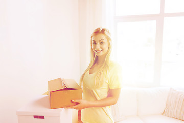 Image showing smiling young woman with cardboard box at home