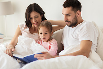 Image showing happy family reading book in bed at home