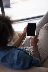 Image showing African american woman at home in chair with tablet and head pho