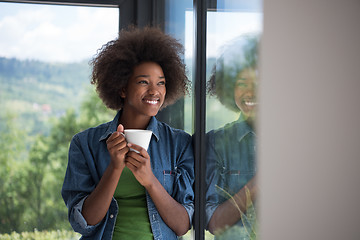 Image showing African American woman drinking coffee looking out the window