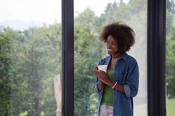 Image showing African American woman drinking coffee looking out the window