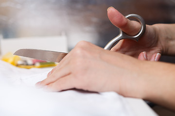 Image showing Woman cuts fabric with scissors