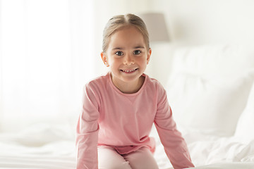 Image showing happy little girl on bed at home bedroom