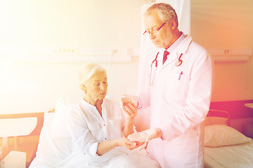 Image showing doctor giving medicine to senior woman at hospital