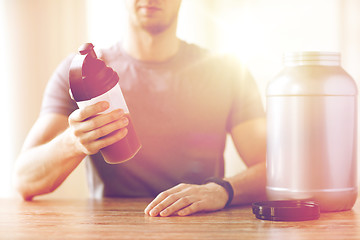 Image showing close up of man with protein shake bottle and jar