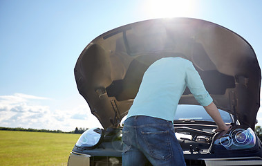 Image showing man with open hood of broken car at countryside