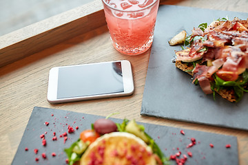 Image showing goat cheese and ham salads with smartphone at cafe