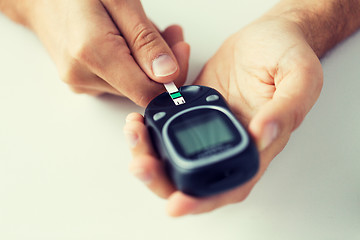 Image showing close up of man checking blood sugar by glucometer