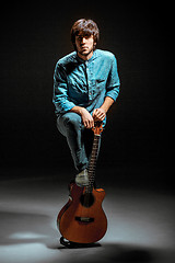 Image showing Cool guy standing with guitar on dark background