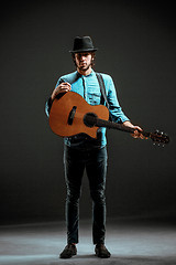 Image showing Cool guy standing with guitar on dark background