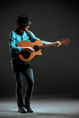 Image showing Cool guy standing with guitar on dark background