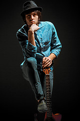 Image showing Cool guy standing with guitar on dark background