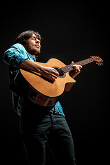 Image showing Cool guy standing with guitar on dark background