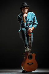 Image showing Cool guy standing with guitar on dark background