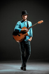 Image showing Cool guy standing with guitar on dark background