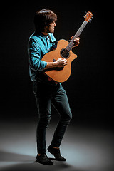 Image showing Cool guy standing with guitar on dark background