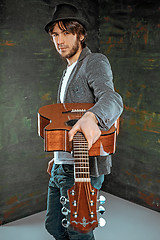 Image showing Cool guy standing with guitar on gray background