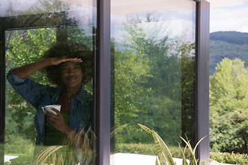 Image showing African American woman drinking coffee looking out the window