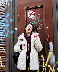 Image showing young pretty stylish teenage girl outside at city wall with graf